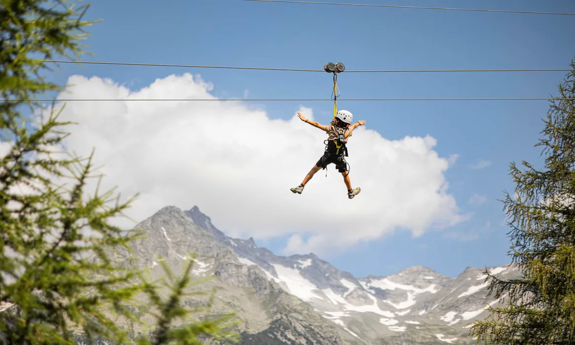 Zipline rider with helmet seen from behind at Speikboden, high alpine scenery with snowfields