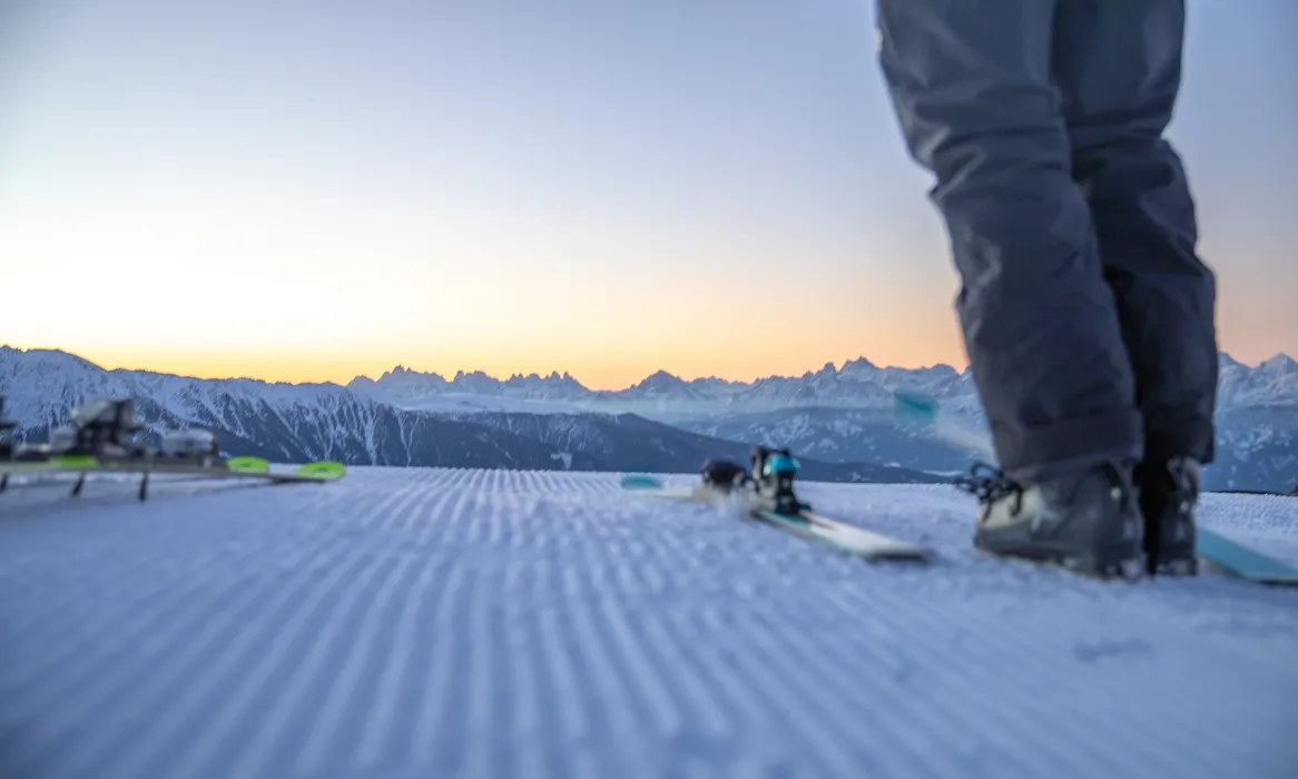 Pista appena preparata all'alba con la sagoma delle Dolomiti, sci first-line al Klausberg