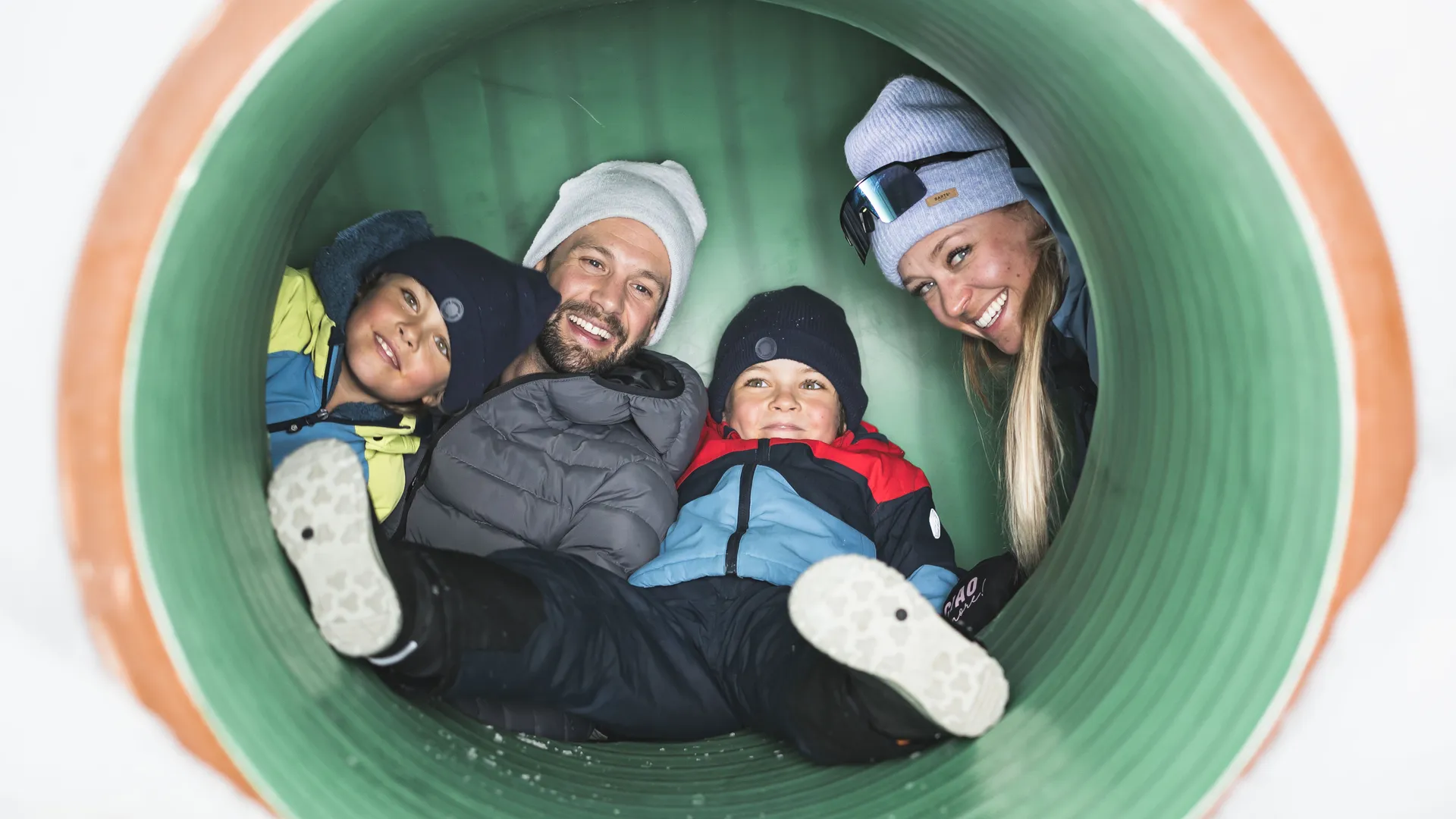 Famiglia ride da un tunnel giochi nel parco bambini della Skiworld Ahrntal nella neve