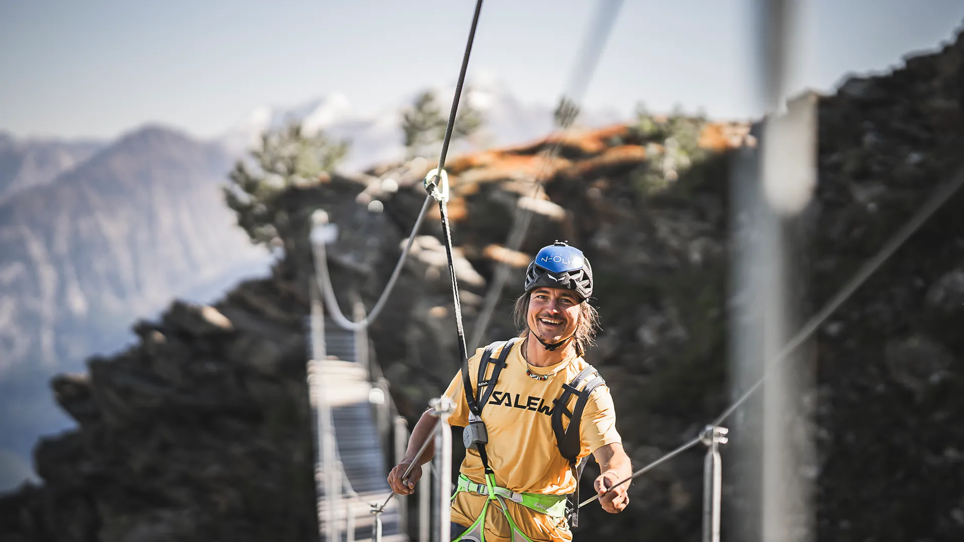 Giovane scalatore su ponte sospeso della via ferrata al Klausberg con vista sulle Alpi