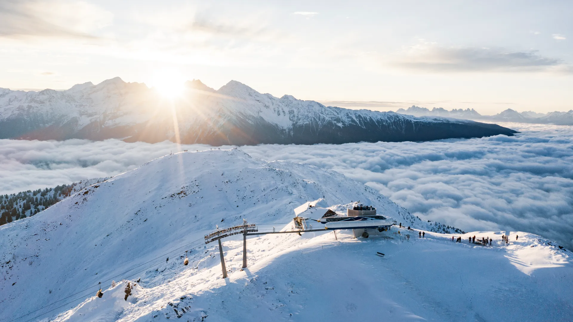 Aerial view of Sonnklar mountain station at golden sunrise above a sea of clouds