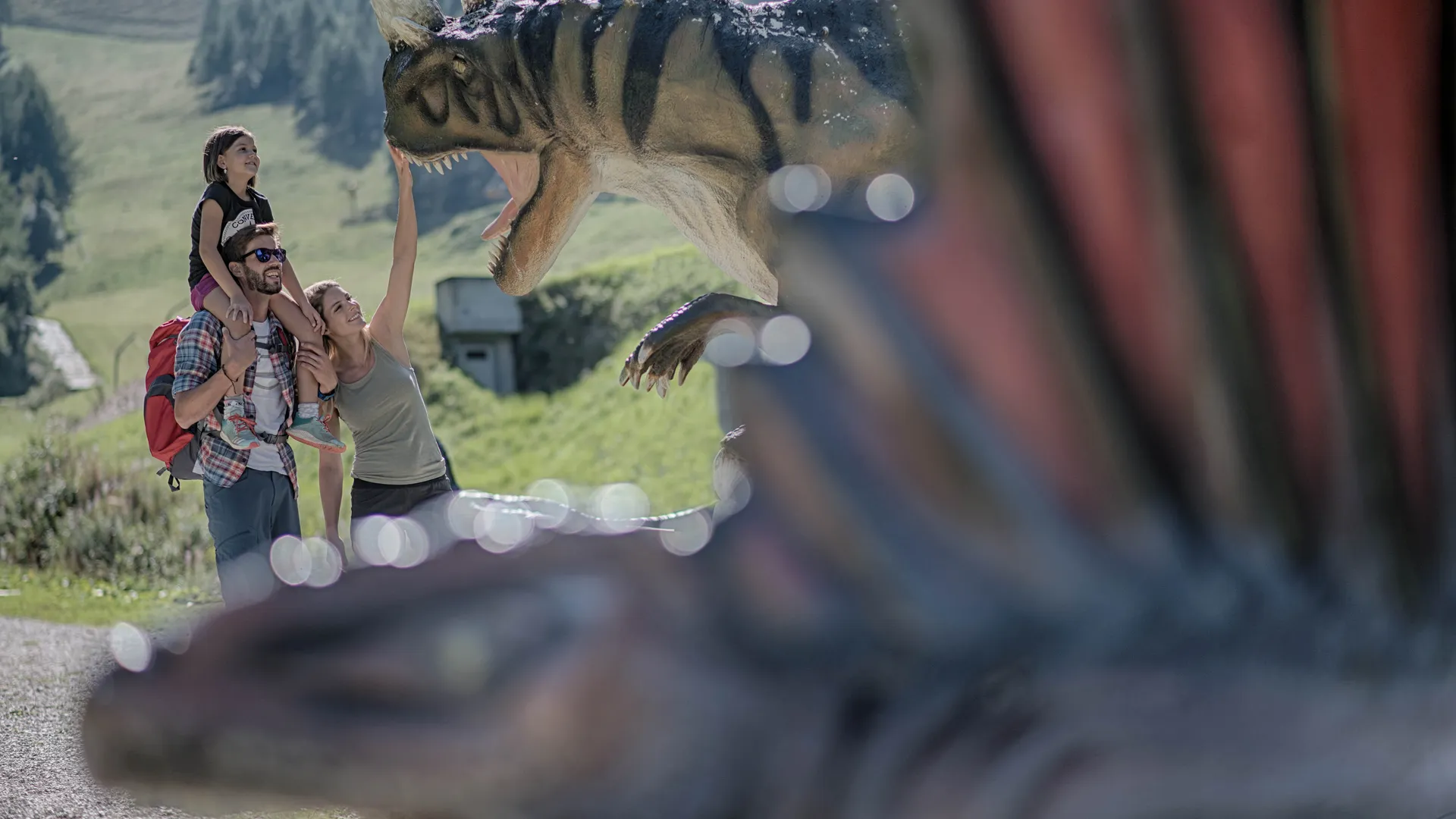 Familie mit Kind entdeckt lebensgroße Dinosaurier-Figur im Dinopark am Klausberg im Ahrntal