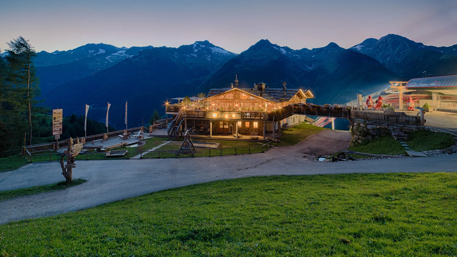 Beleuchtete Almhütte bei Sonnenuntergang mit Panoramablick auf die Zillertaler Alpen am Klausberg