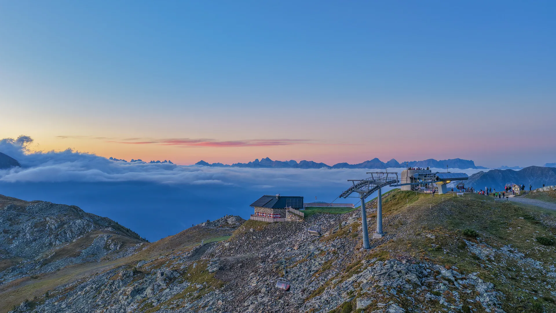 Mountain station with chairlift at Klausberg at sunset above sea of clouds with Dolomites panorama