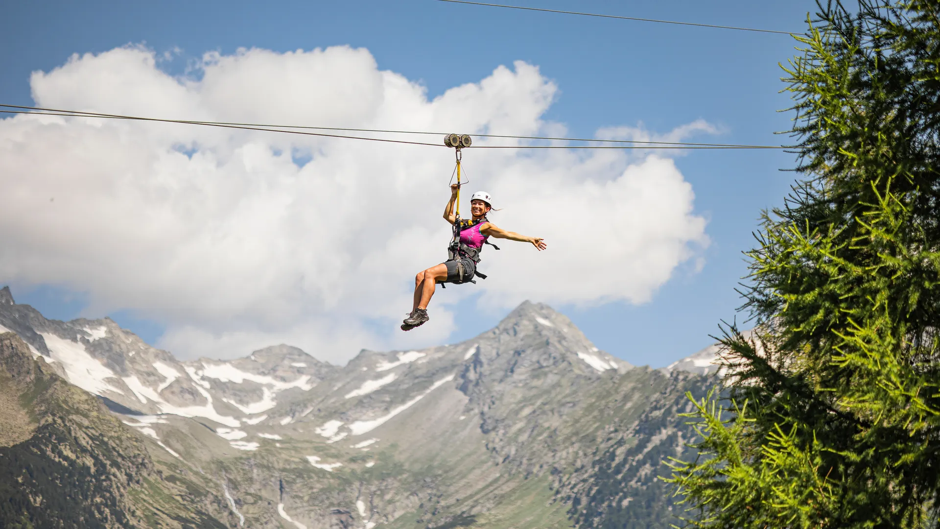 Woman on Skyglider zipline at Klausberg in front of snow-capped Zillertal Alps