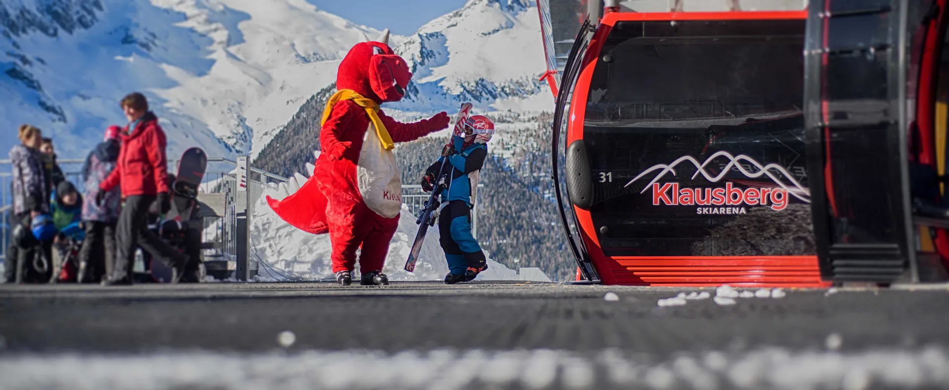 Dragon mascot welcoming a child at the Klausberg mountain station with alpine panorama