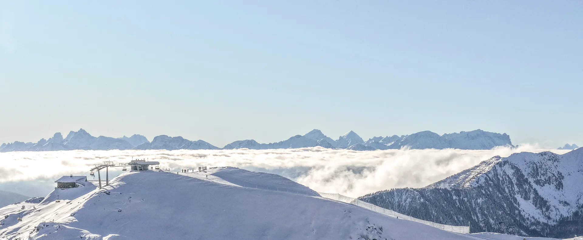 Mountain station at Speikboden with chairlift above cloud sea and Dolomites in the background