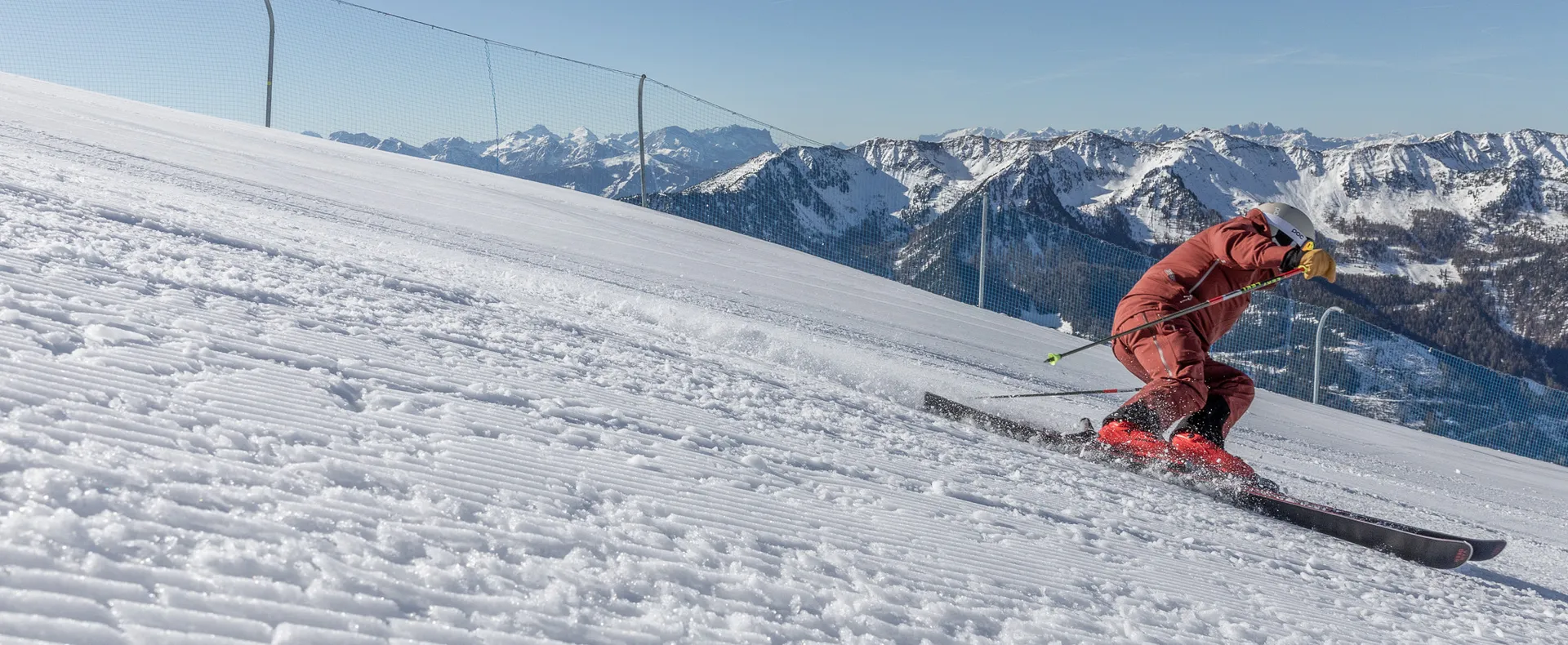 Skier in red suit carving on a perfectly groomed slope at Klausberg