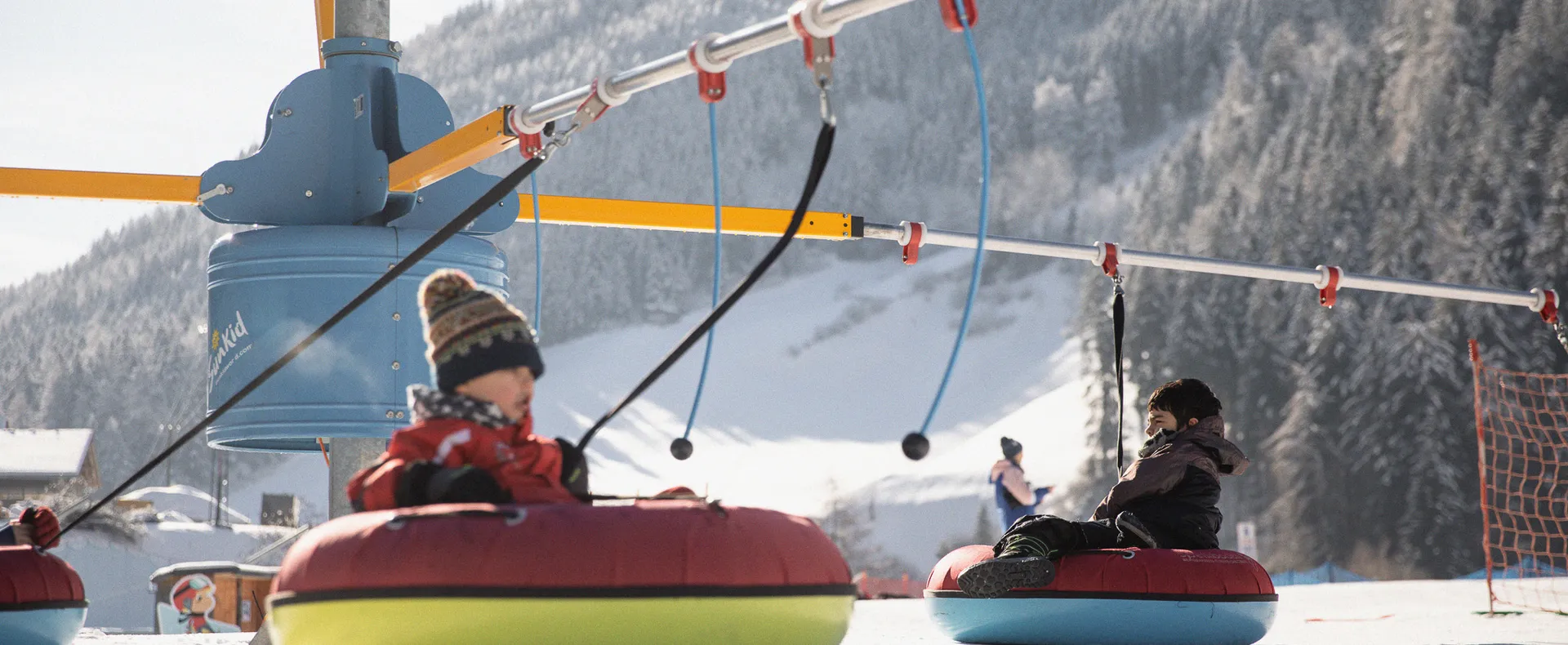 Bambini su snow-tube colorati sulla giostra del tubing nel parco giochi invernale in Valle Aurina