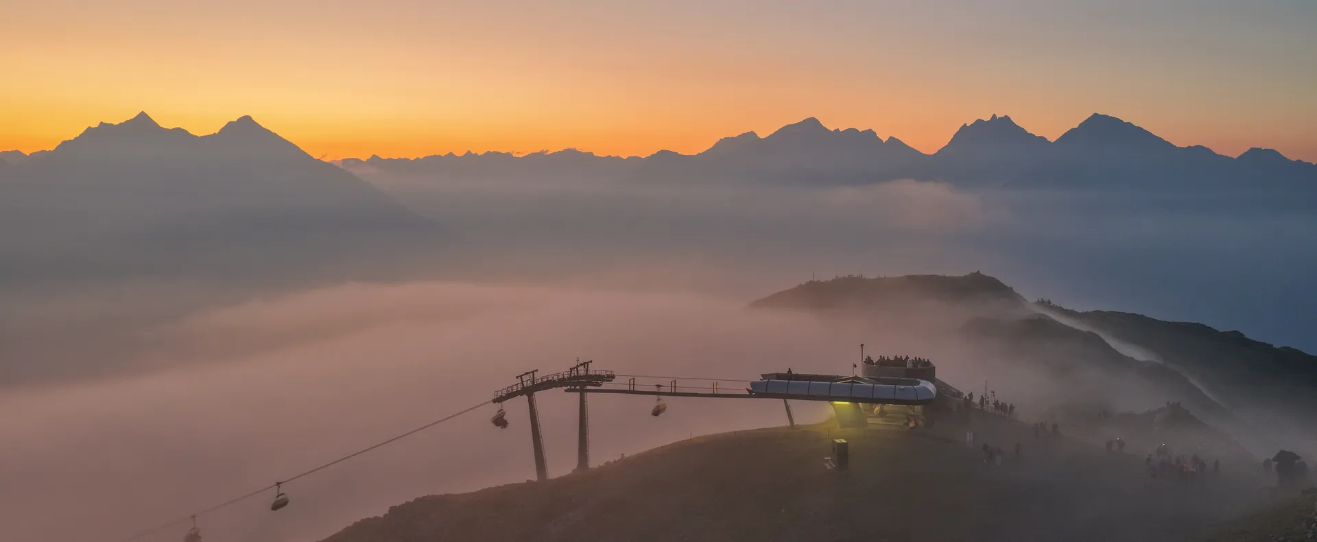 Cabine della funivia al Klausberg al tramonto con mare di nebbia e vette alpine