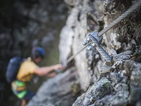 Arrampicatore afferra il perno roccioso al via ferrata Speikboden — dettaglio ancoraggio