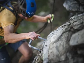 Mano afferra il piolo metallico al via ferrata Speikboden — dettaglio tecnica