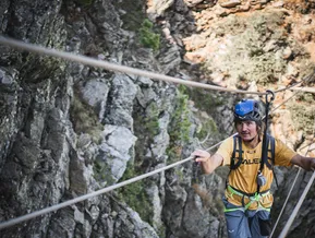 Arrampicatore al ponte via ferrata Speikboden si tiene ai cavi d'acciaio