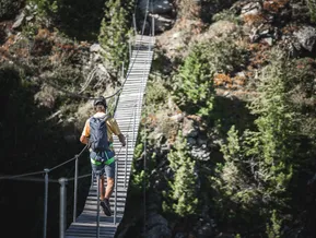 Arrampicatore attraversa il ponte in legno sospeso al via ferrata Speikboden