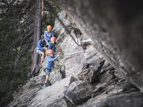 Family via ferrata at Speikboden — group of four people climbing rocky route