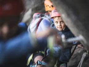 Child in climbing helmet looking upward on Speikboden via ferrata route