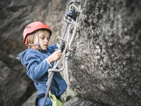 Child clipping via ferrata set onto steel cable — safety technique at Speikboden