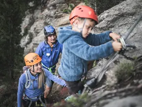 Guided via ferrata at Speikboden — child with mountain guides on rock face
