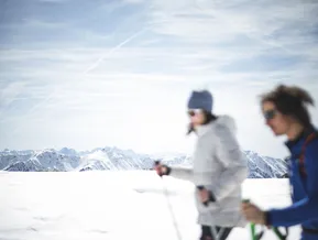 Due escursioniste con ciaspolette davanti al vasto panorama delle Alpi della Zillertal in Valle Aurina
