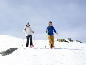 Due escursionisti con ciaspolette in salita su un pendio innevato e roccioso al Klausberg in Valle Aurina