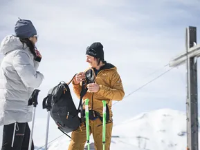 Guida alpina spiega l'attrezzatura da ciaspolette alla croce di vetta dello Speikboden in una giornata invernale soleggiata