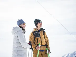 Coppia sorridente con bastoncini da ciaspolette e abbigliamento invernale sulla vetta in Valle Aurina
