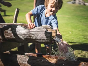 Kind spielt fröhlich am Wasserspielplatz am Klausberg im Ahrntal