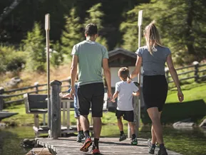 Familie spaziert über Holzsteg am Bergsee im Ahrntal