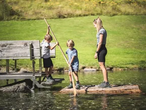 Kinder staken auf Holzfloß am Bergsee beim Klausberg Ahrntal