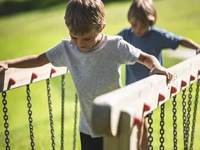 Zwei Jungen balancieren auf Kettenbrücke im Erlebnispark Klausberg
