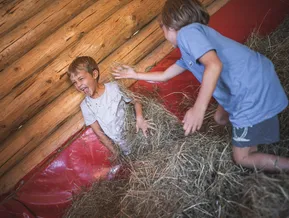 Zwei Kinder toben fröhlich im Heu auf einem Bauernhof im Ahrntal