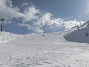 Wide groomed ski slope at Klausberg in Ahrntal with red gondola lift and clear blue winter sky