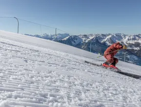 Skier in red suit carving on a perfectly groomed slope at Klausberg
