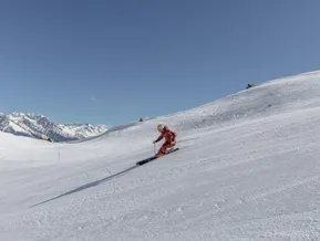 Female skier in red clothing on a freshly groomed slope at Klausberg with mountain panorama