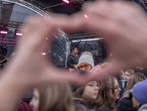 Konzert-Atmosphäre – Fans formen Herz mit Händen vor Sänger mit Gitarre auf der Bühne