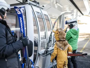 Kinder steigen in die Gondelbahn ein – Skitag mit der Familie am Klausberg oder Speikboden