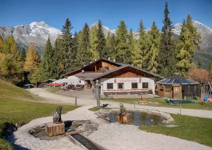 Almhütte Almboden mit Teich und Spielbereich, herbstliche Lärchen und Schneeberge