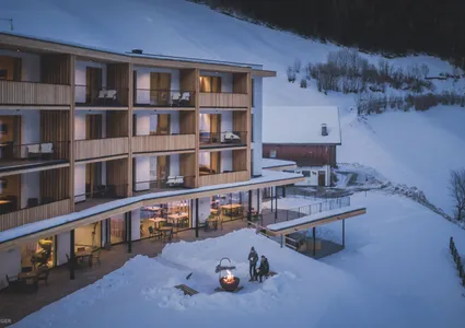Design-Hotel Ahrntal bei Dämmerung mit Après-Ski Feuerstelle im Schnee