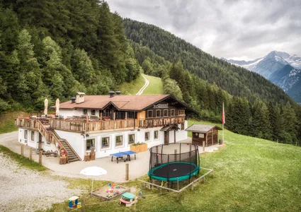 Bergrestaurant Alm mit Spielplatz für Kinder und Bergpanorama im Sommer