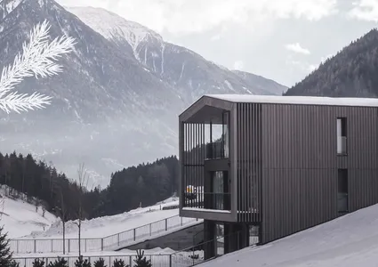 Modernes Design-Chalet mit Holzfassade vor Bergpanorama im Winter Ahrntal