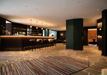 Gemütliche Hotelbar mit Natursteinboden und Fellhockern im Ahrntal