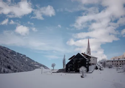 Verschneites Bergdorf mit Kirche im Ahrntal – Winterurlaub Klausberg