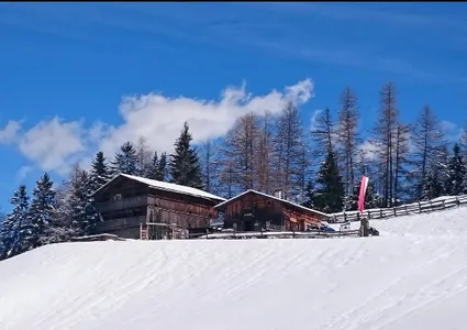 Almhütte mit schneebedecktem Dach und roter Fahne, Ahrntal im Winter