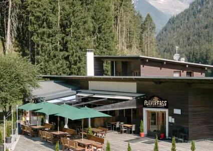 Pulverfass Après-Ski-Bar und Pizzeria mit Sonnenterrasse und grünen Sonnenschirmen