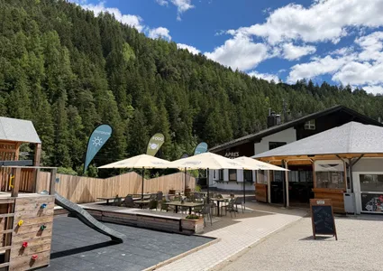 Terrazza esterna soleggiata con ombrelloni e rifugio ai piedi della montagna in Valle Aurina