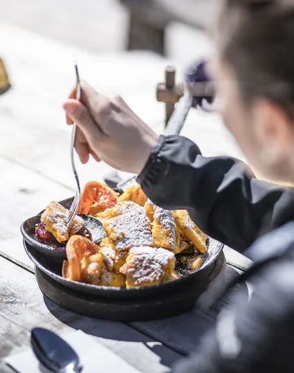 Kaiserschmarrn in a pan on a rustic wooden table at a ski hut in Ahrntal