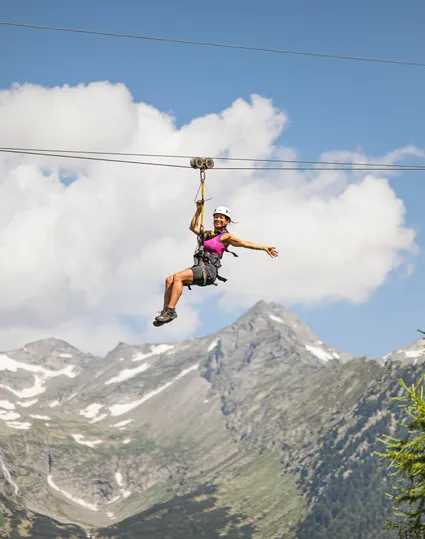 Frau am Skyglider Zipline am Klausberg vor schneebedeckter Zillertaler Alpenkette