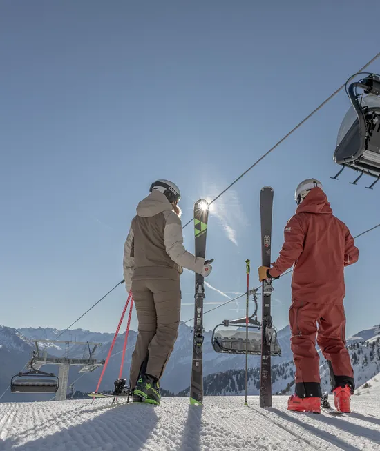 Zwei Skifahrer an der Bergstation der Sesselbahn am Speikboden mit Blick auf Südtiroler Alpen