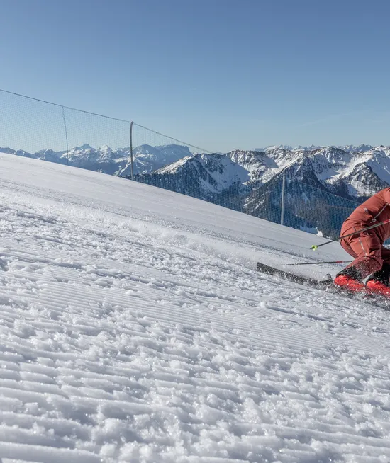 Skifahrer im roten Anzug beim Carving auf perfekt präparierter Piste am Klausberg