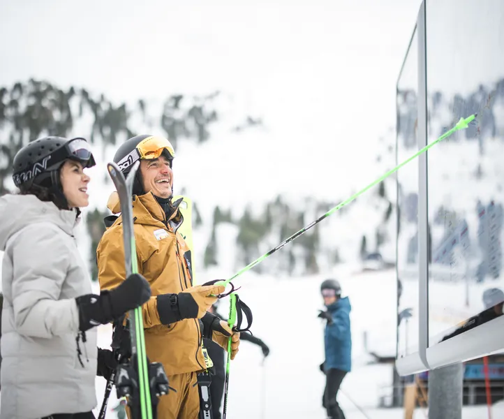 Two laughing skiers studying the panoramic board with the piste map of Skiworld Ahrntal
